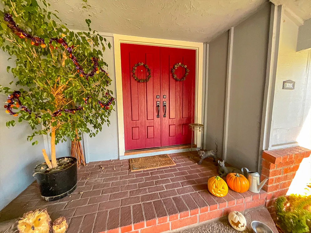 Front entry with red double doors surrounded by old siding