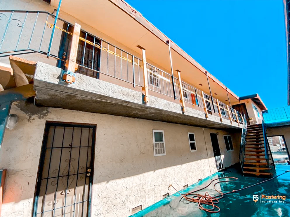 Apartment balcony edge with new stucco and temporary railing supports