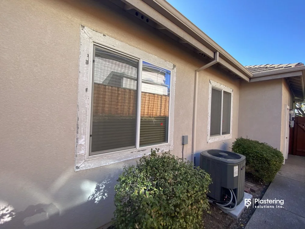 Replacement windows with primed patches beside an air conditioning unit