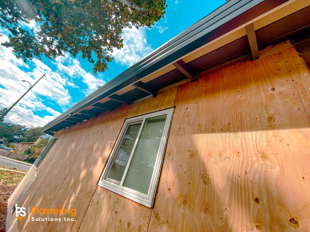 New plywood sheathing installed on an exterior wall around a window under the eave