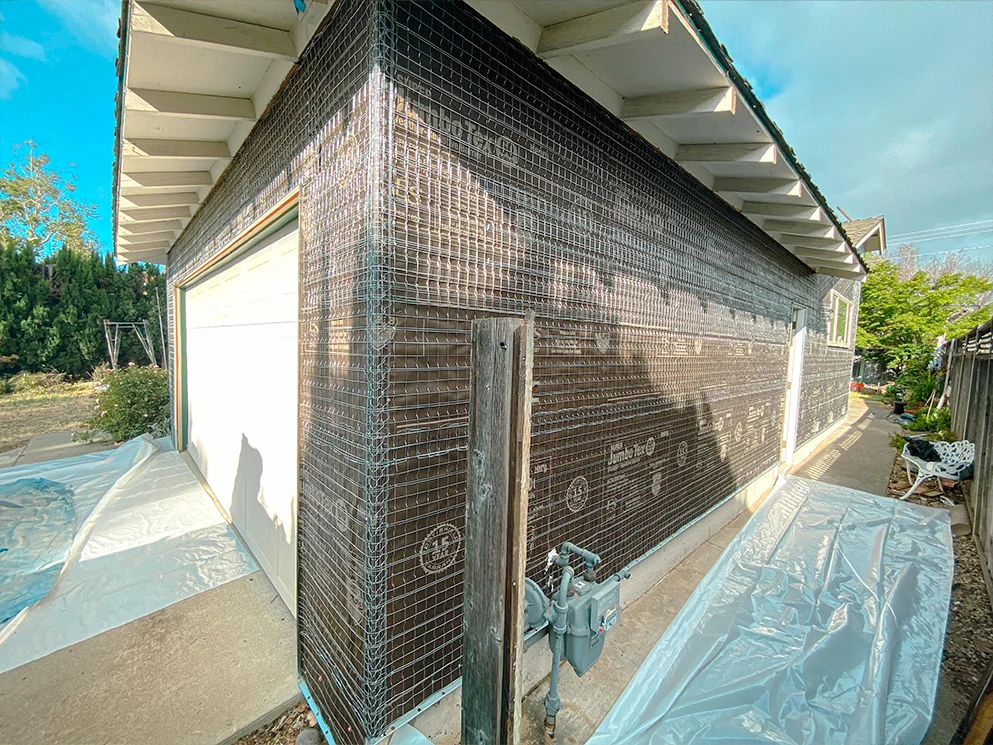 Garage corner wrapped in lath with the walkway protected