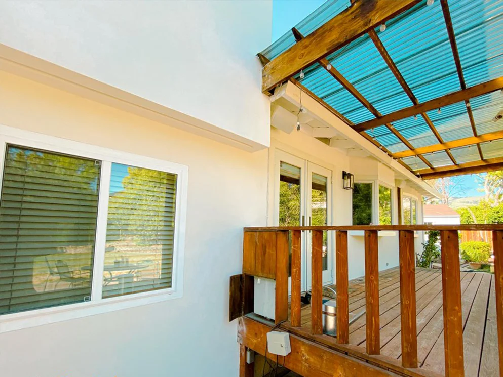 Finished smooth acrylic stucco around a window beside the covered deck