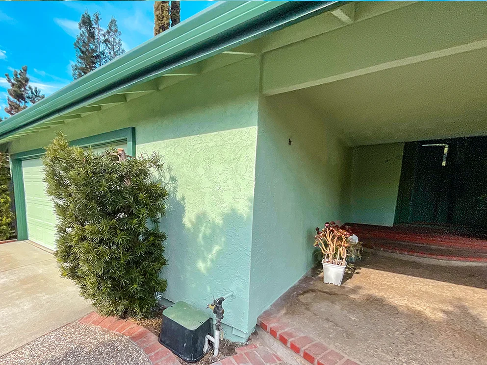 Finished green stucco on the front corner beside the covered entry