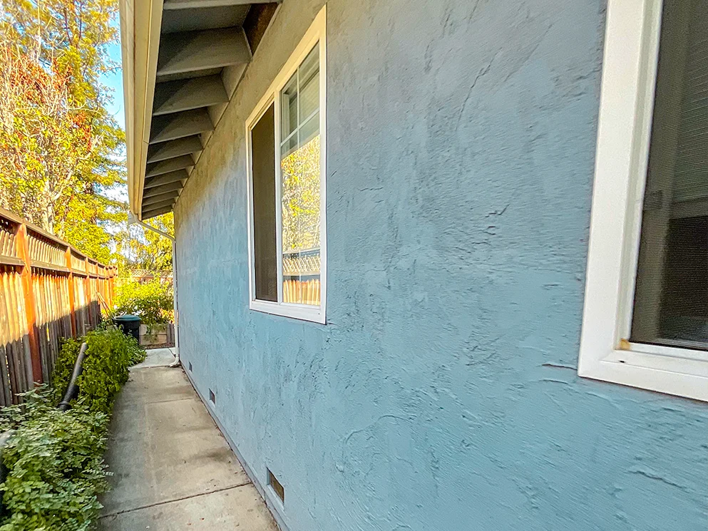 Side yard wall with existing stucco beside a narrow walkway