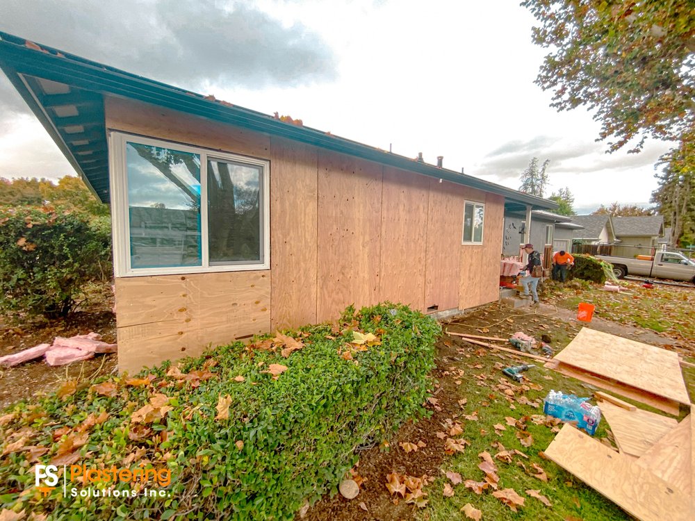 New plywood sheathing installed over the wall framing beside a window