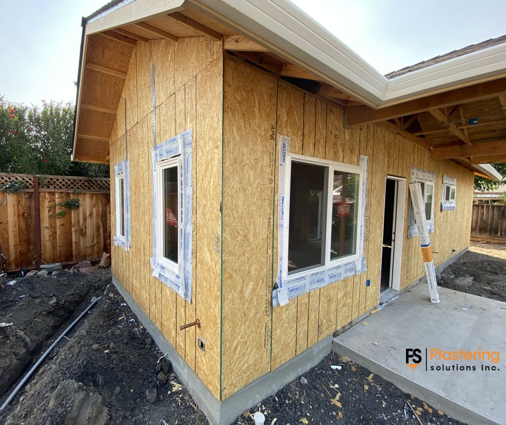 Corner of the new home with sheathing and masked windows ready for weather barrier