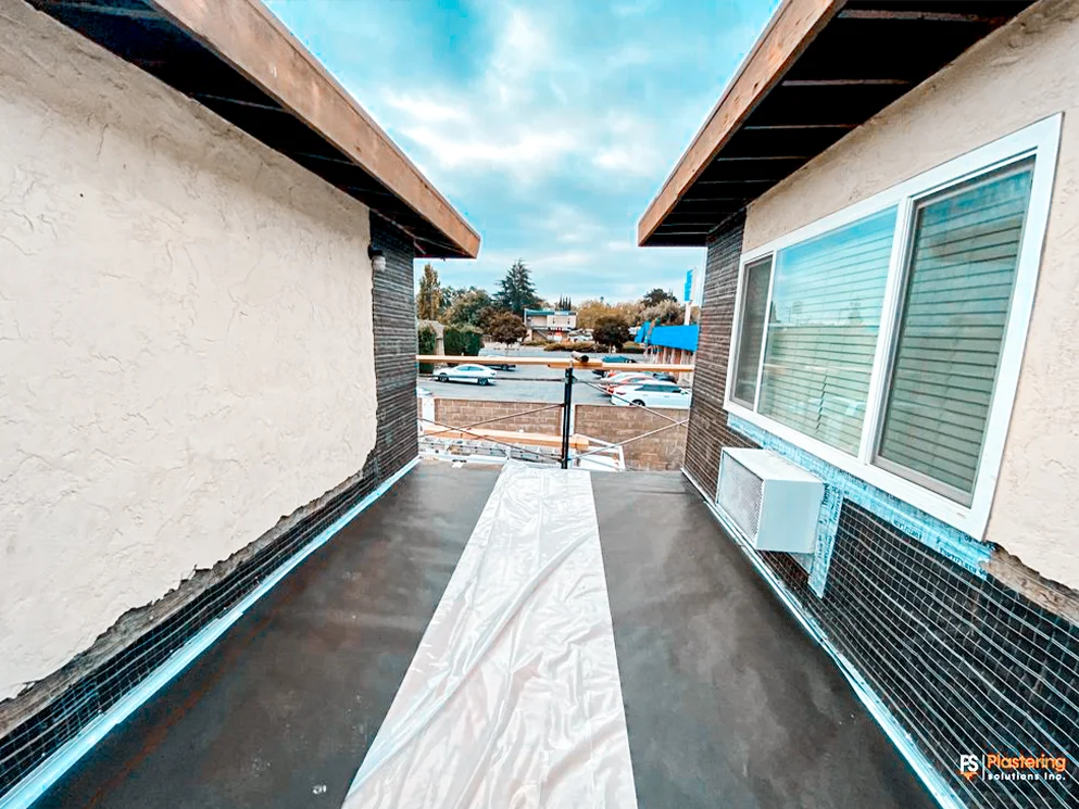 Upper apartment walkway with weather barrier and metal lath along the wall base