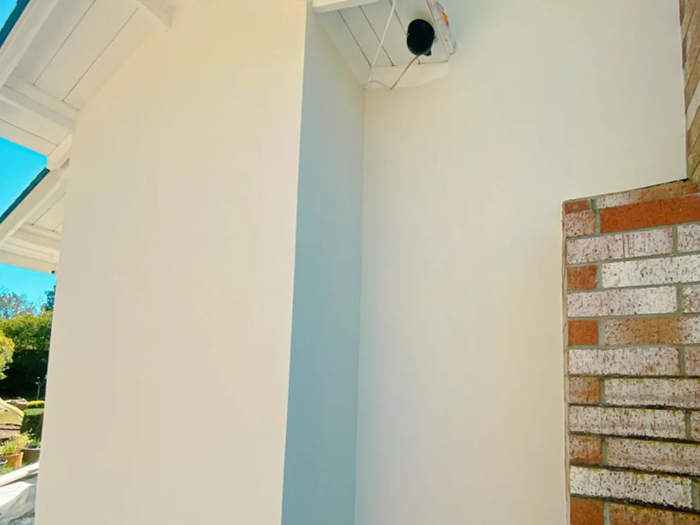 Close view of the finished smooth acrylic stucco beside a brick chimney