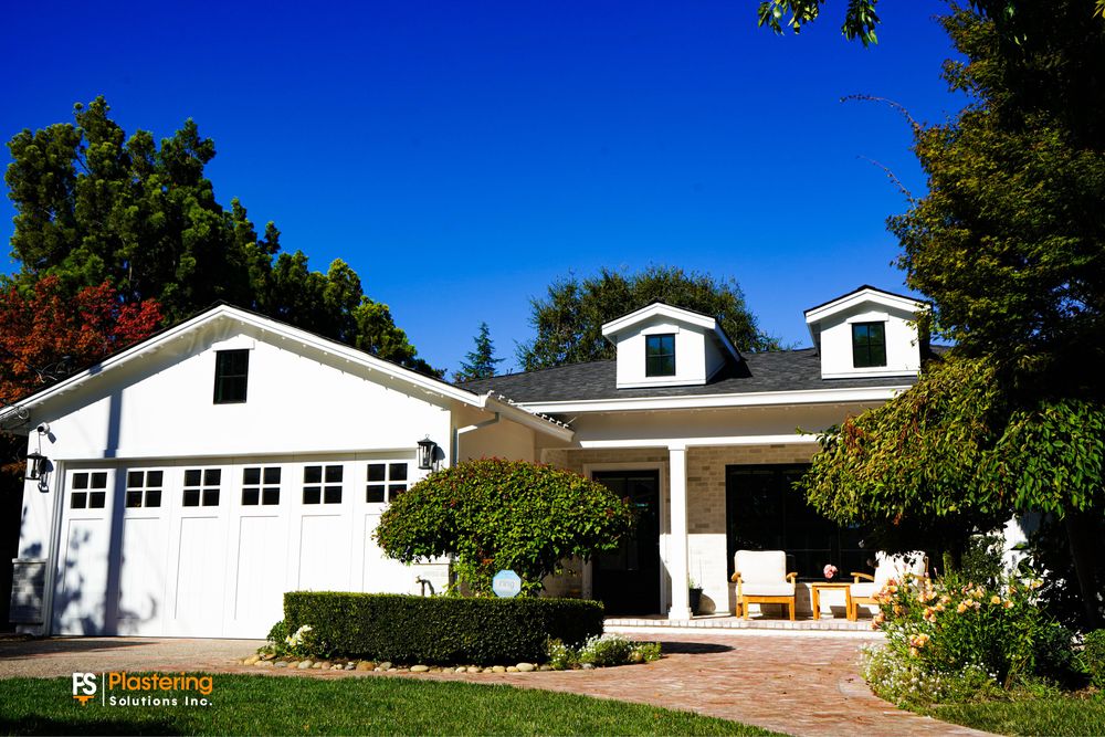 White ranch home with fresh smooth stucco, dormers and a brick walkway