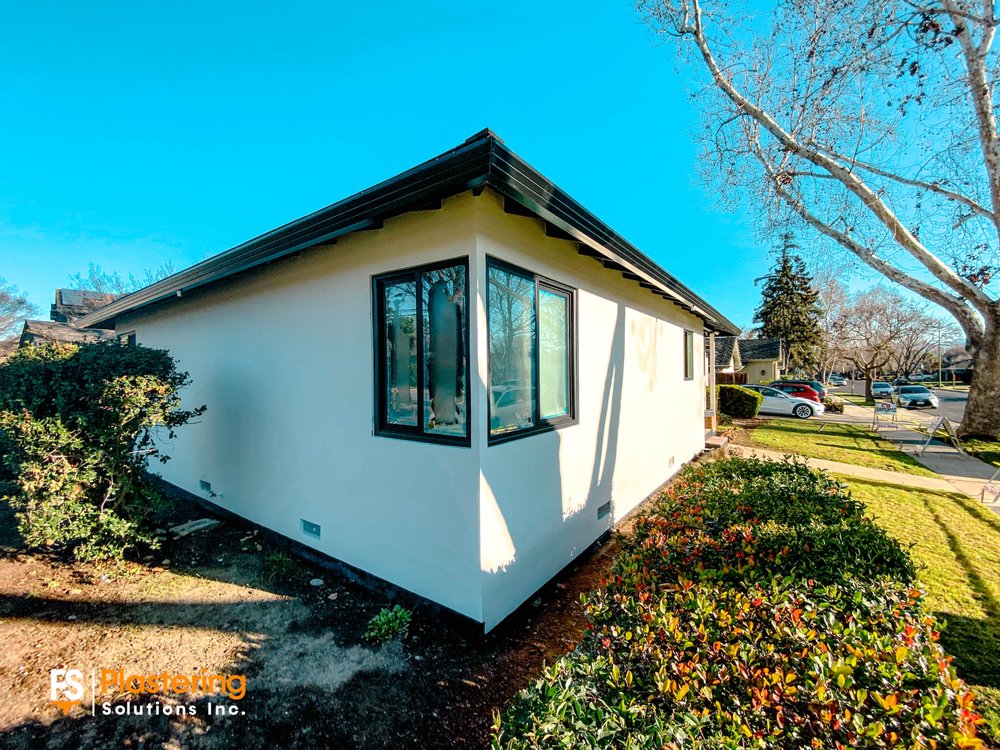 Home corner with finished smooth stucco and new dark framed windows