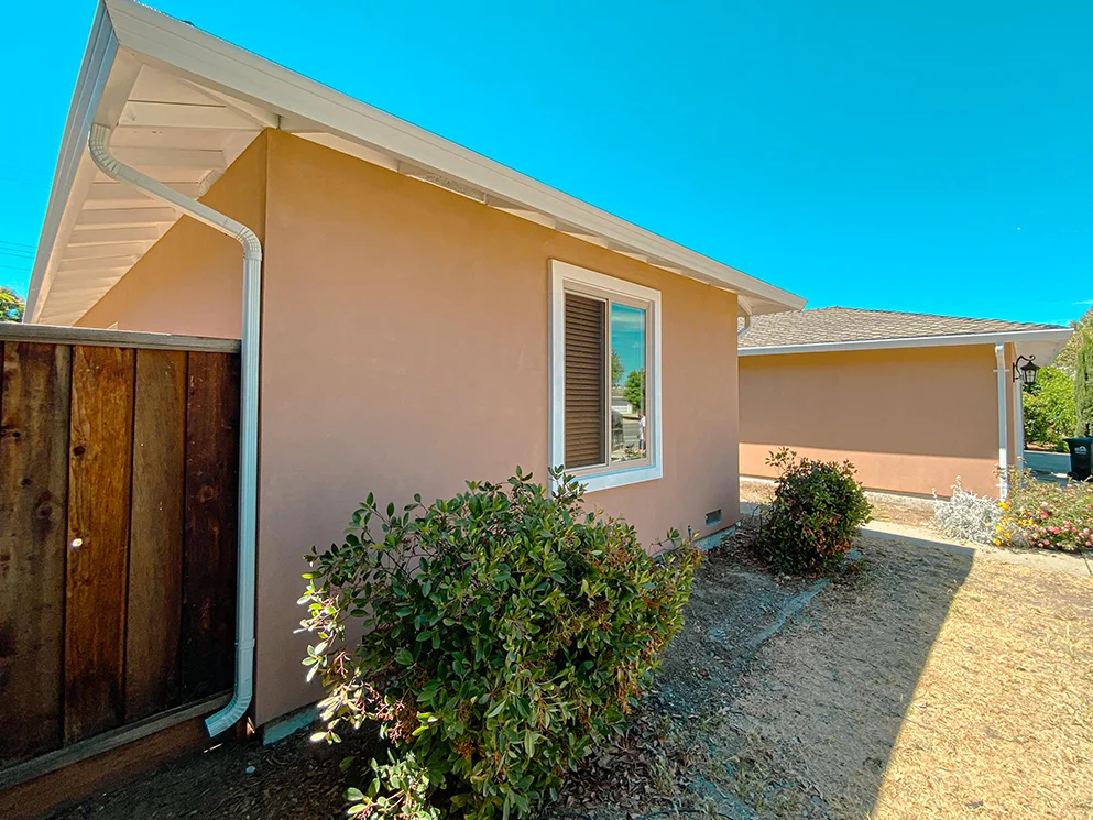 Side of the home with the completed acrylic smooth stucco and new gutters