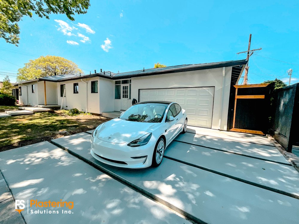 Completed home exterior with smooth integrated color stucco and garage