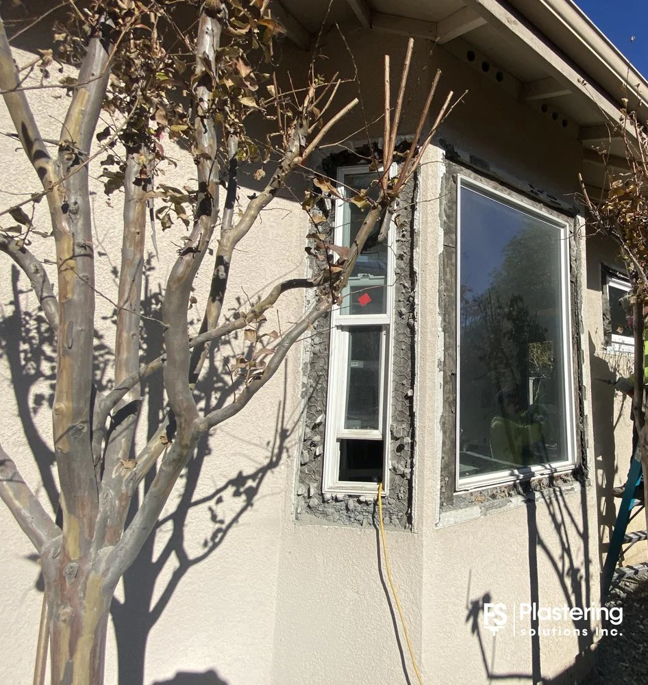 Corner windows with lath exposed around the frames beside a tree