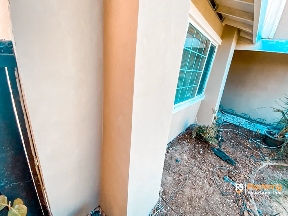 Finished stucco corner and side wall beside a window