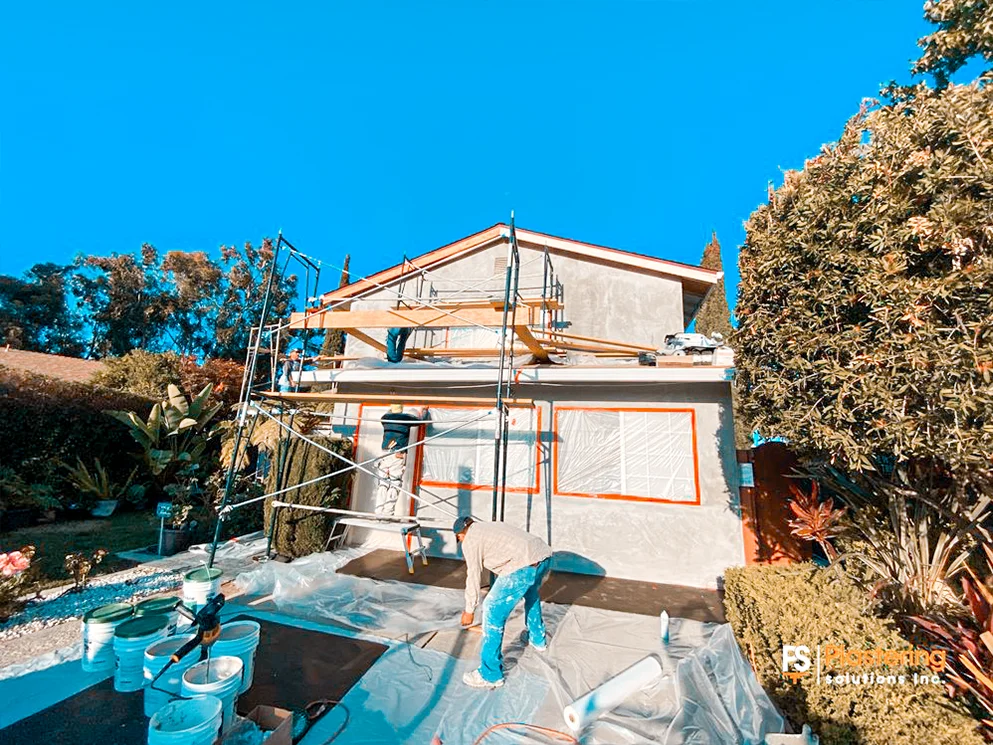 Crew preparing the finish coat with windows masked and the driveway protected