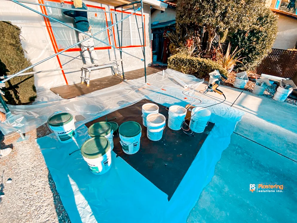 Acrylic finish buckets and sprayer set up on a protected driveway
