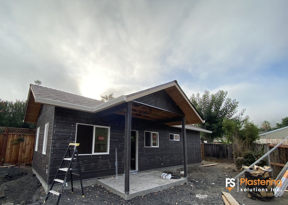 New home covered in weather barrier and wire lath with the porch posts in place