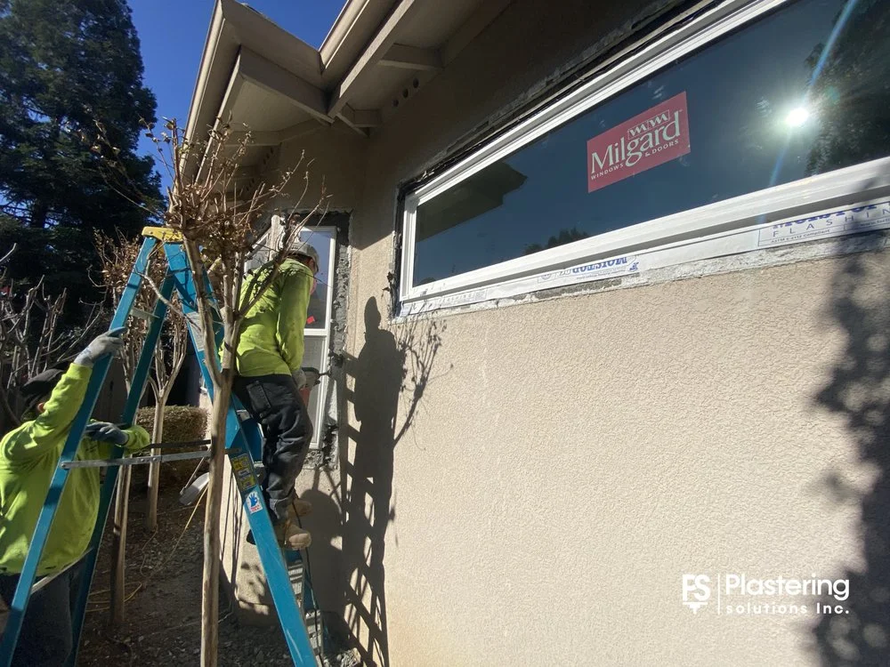 Crew on a ladder installing flashing around a new window