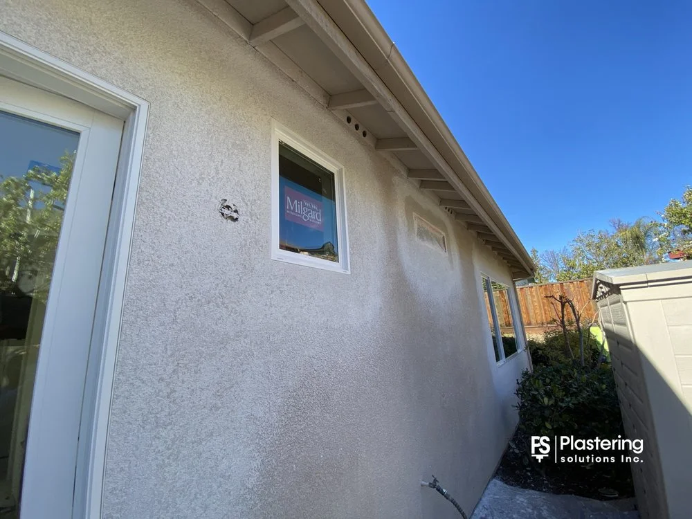 Finished stucco around a new window beside a patio door