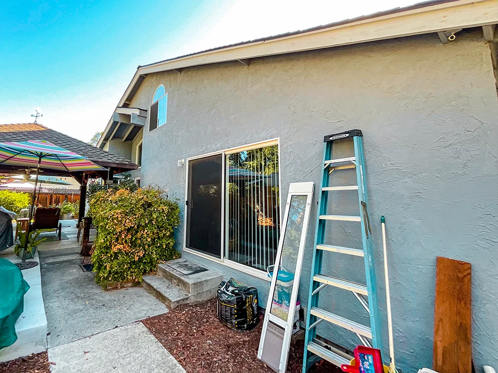 Rear elevation with a sliding door and ladder before work began