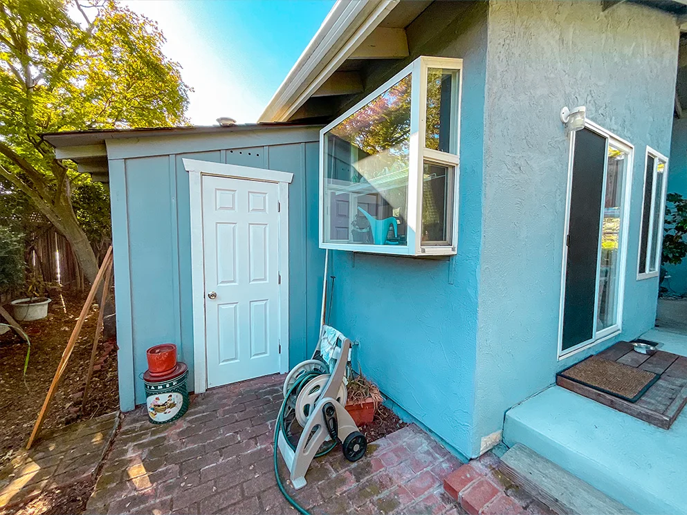 Storage shed with board siding beside the rear wall of the home