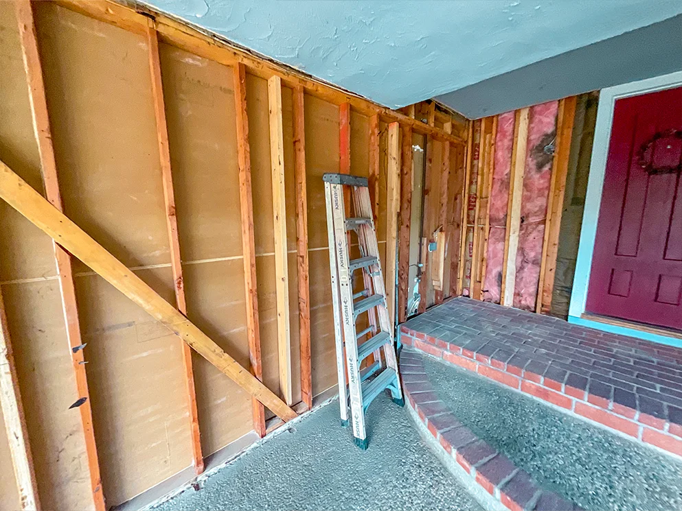Exposed studs and old sheathing along the covered entry
