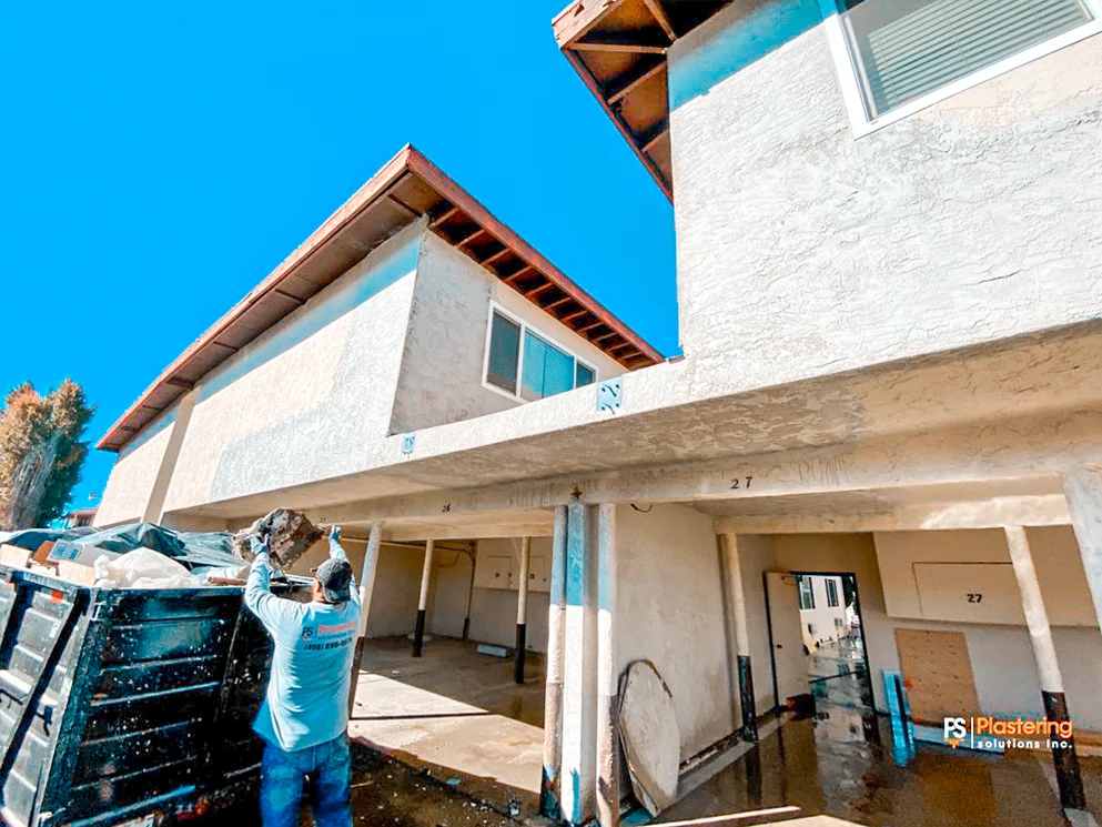 Crew member removing exterior material from a two story apartment building