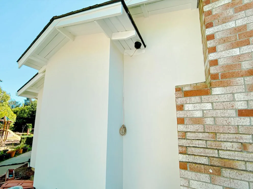 Finished smooth acrylic stucco corner where the wall meets the brick chimney