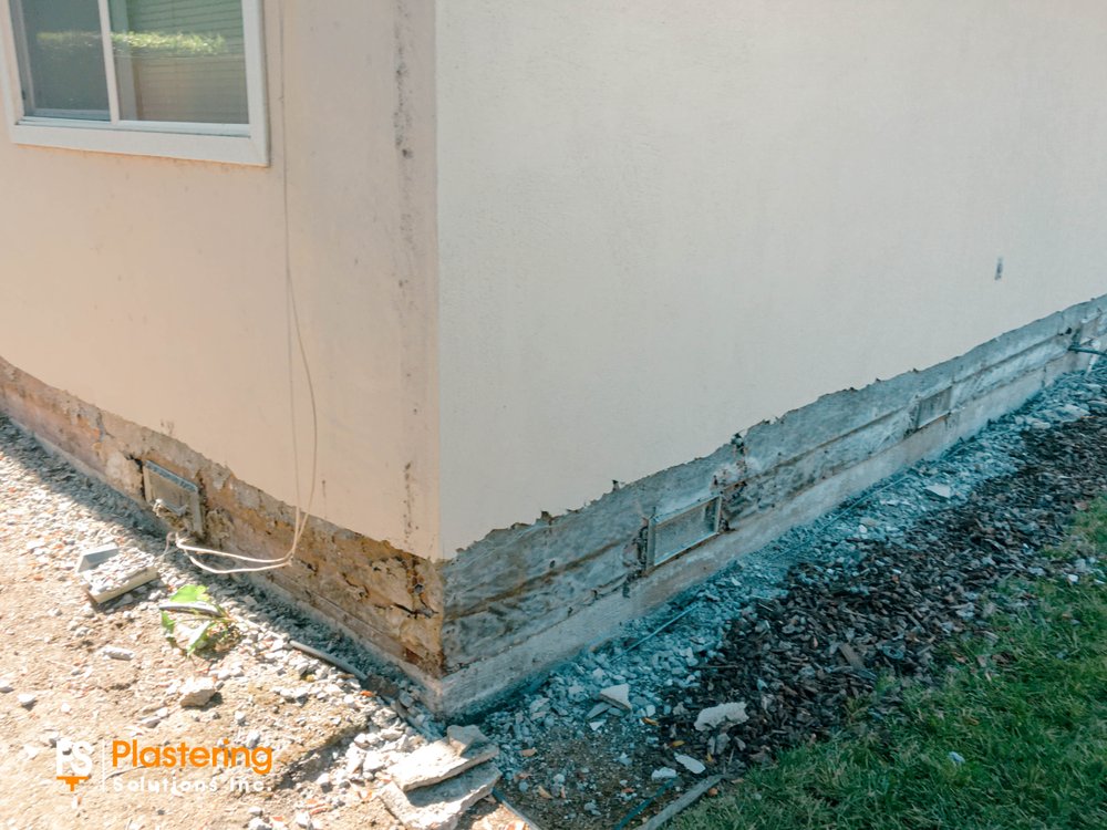 Damaged lower stucco wall at a home corner opened for repair before the new finish