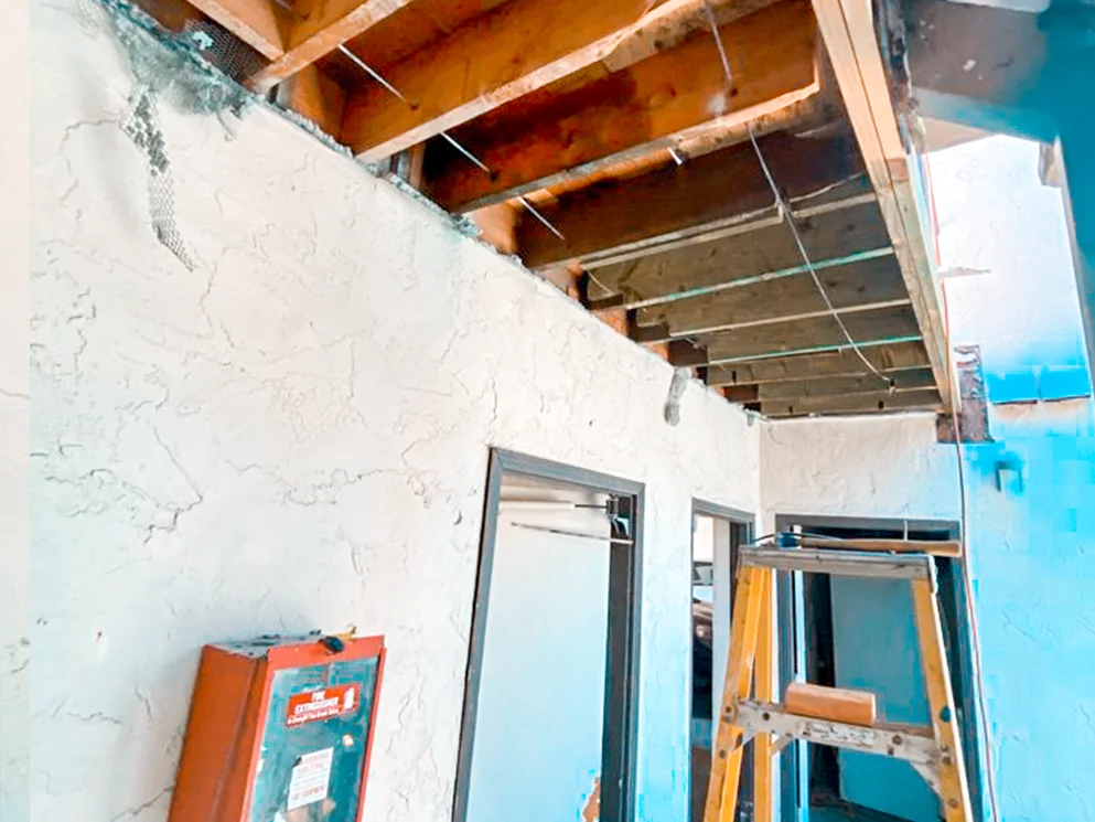 Demolished walkway structure with framing exposed for rebuilding