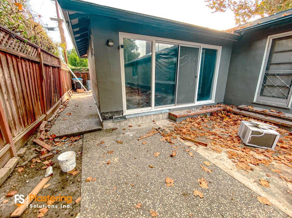 Back of the home with lath installed along the base below a sliding door