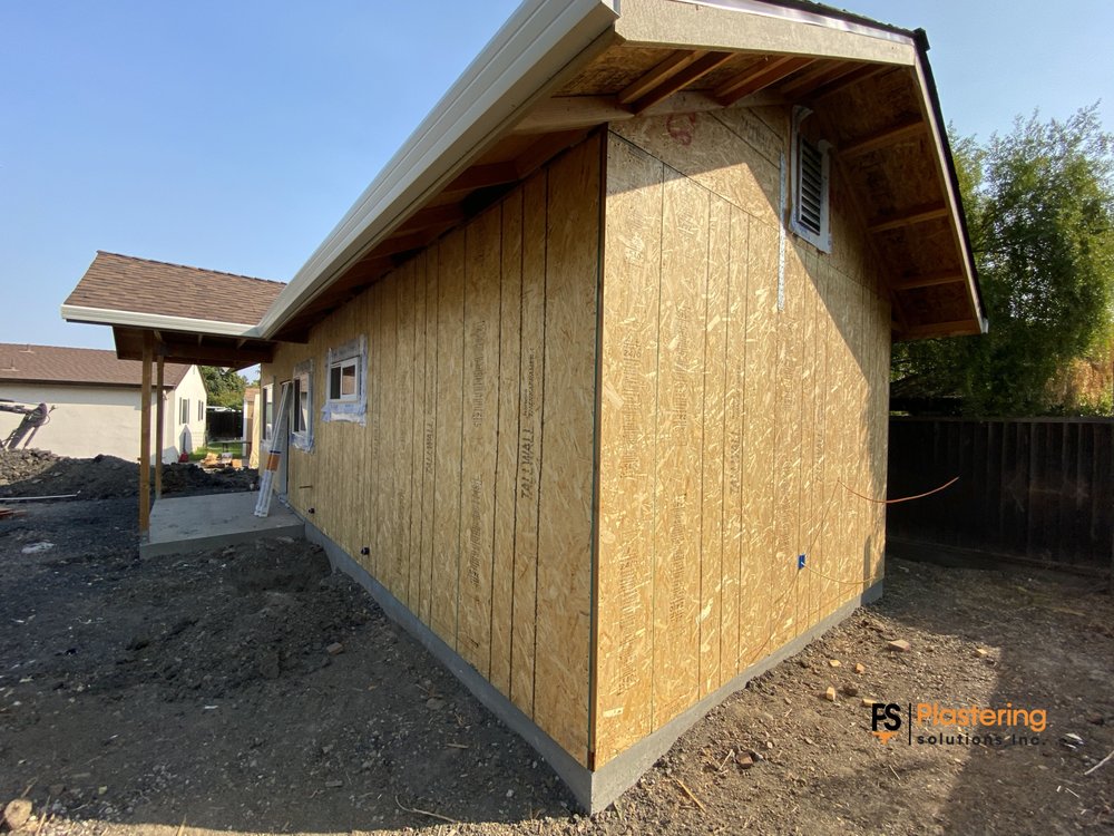Side elevation of the new build with plywood sheathing and porch framing