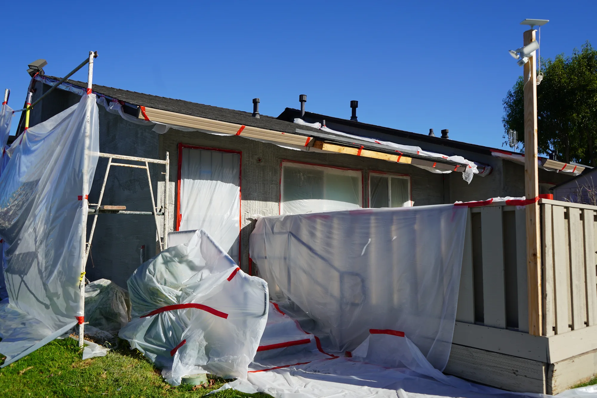Rear apartment patio with doors, windows, and fencing protected before stucco work