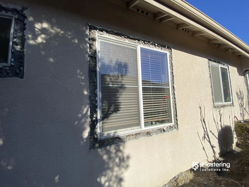 Replacement window with stucco removed around the frame and lath exposed
