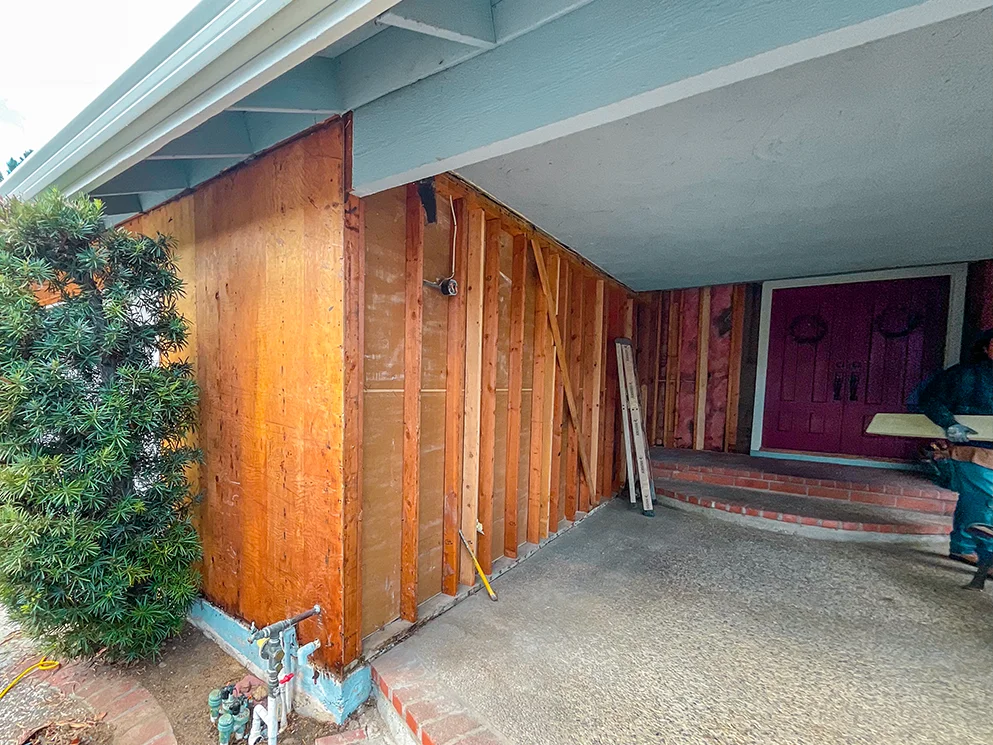 Siding removed from the front wall to expose the framing beside the entry