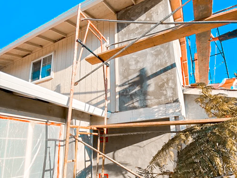 Base coat stucco on the upper wall seen through the scaffolding