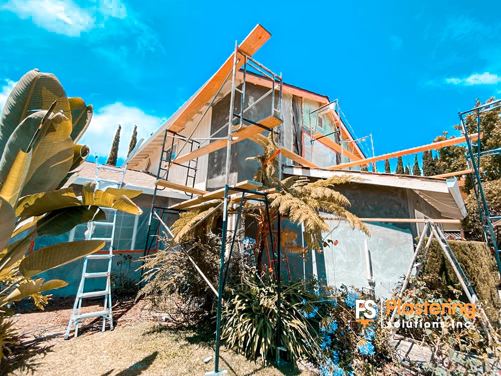 Scaffolding and brown coat stucco on the upper walls of the home