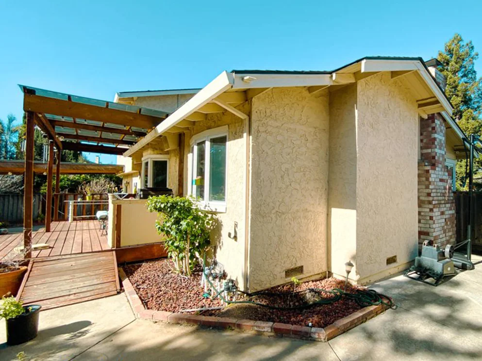 Finished smooth acrylic stucco on a rear wing beside a wood deck and pergola