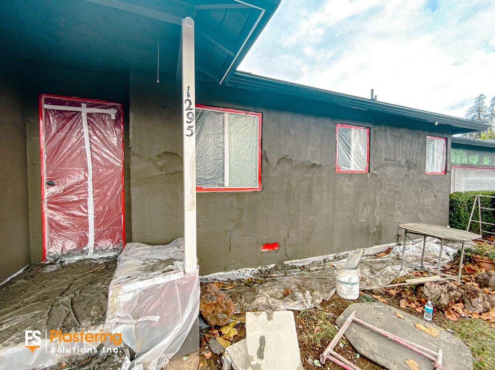 Front of the home with doors and windows masked during the scratch coat