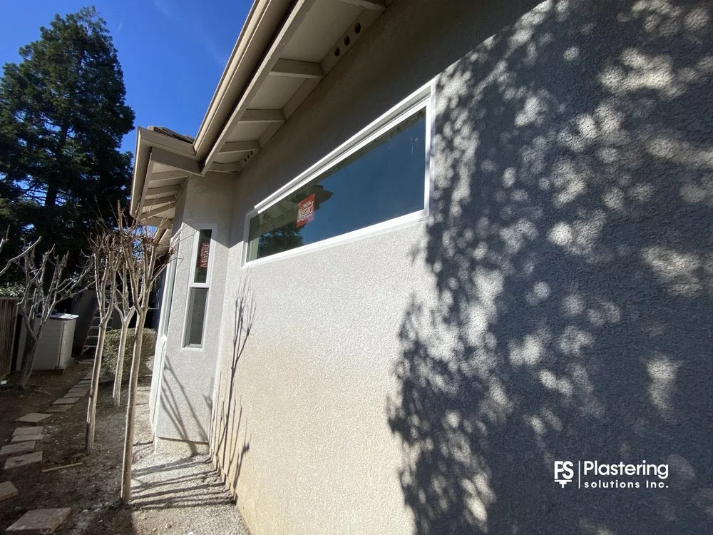 Finished stucco around a new wide window and narrow side window