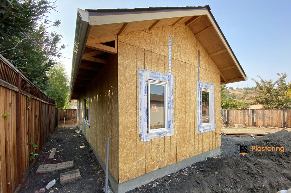 Narrow side yard with sheathing installed and windows taped ahead of stucco