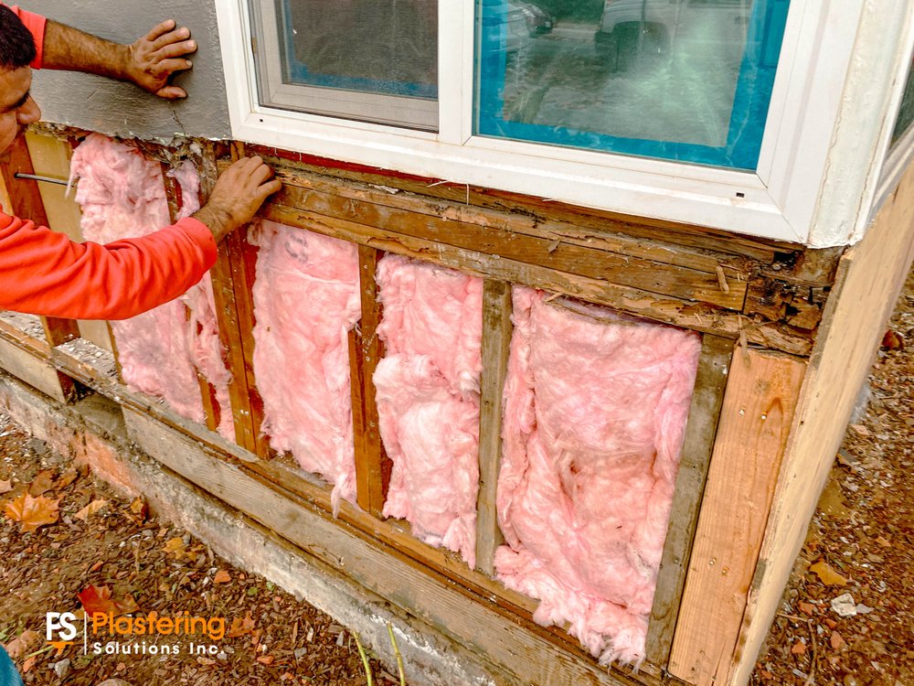 Crew installing insulation between studs around a window opening
