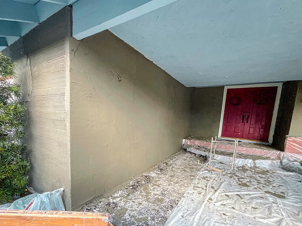 Scratch coat applied along the porch walls with the entry protected