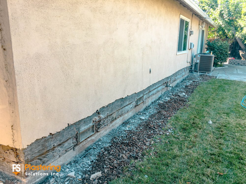 Side of the home with the deteriorated stucco base removed along the foundation