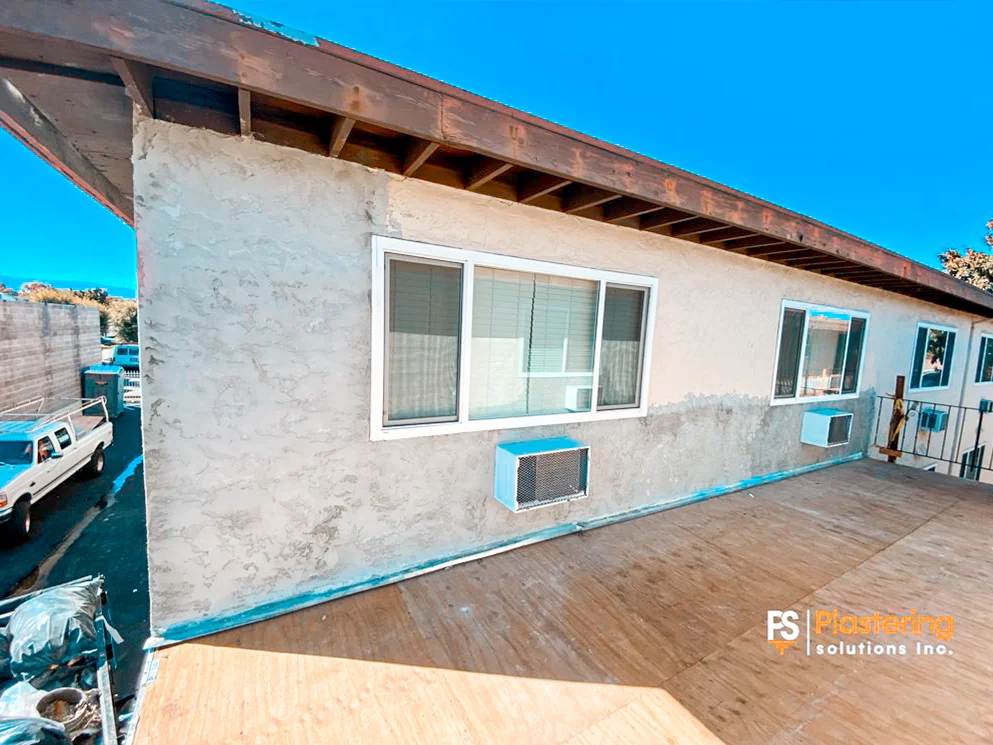 Apartment exterior wall with stucco patch areas below the windows