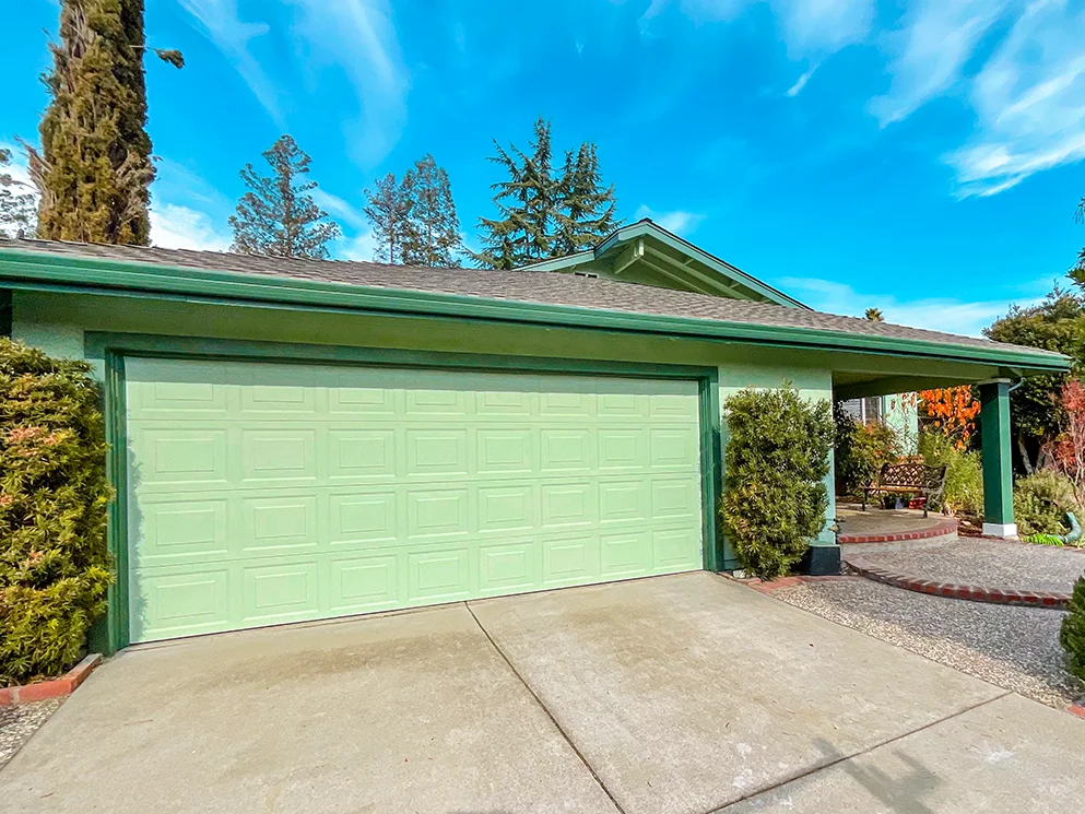 Garage and covered entry with the finished green stucco