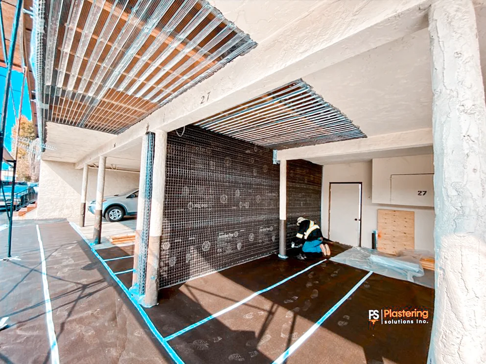 Apartment entry walls covered with weather barrier and metal lath during stucco preparation