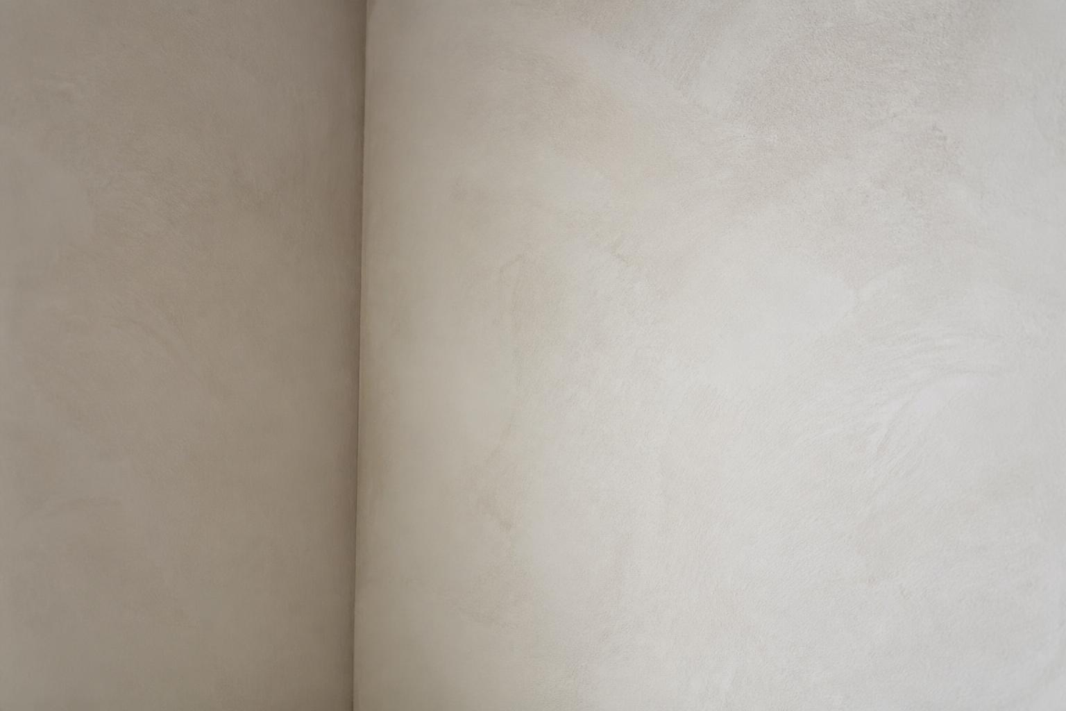 Corner of a limewashed wall in soft chalky white with faint brush movement across the surface