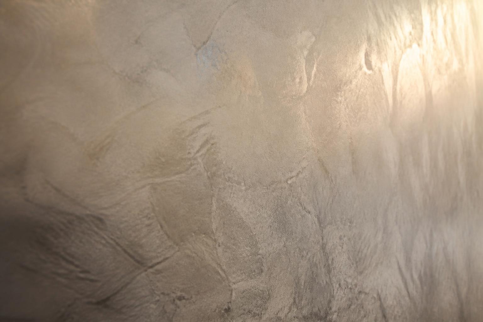 Raking light across a burnished Venetian plaster wall showing the depth and movement of the trowel work