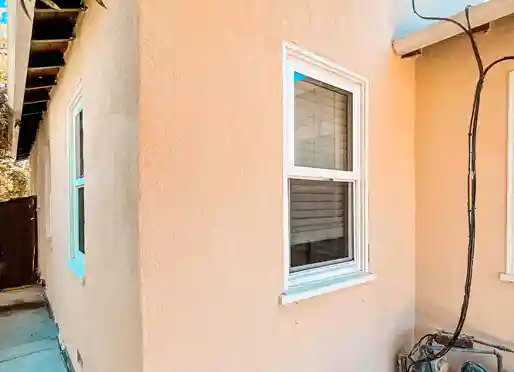 Smooth peach stucco exterior wall around a white double-hung window
